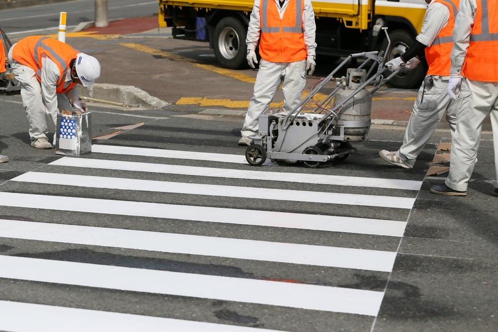 Municipal public works crew applying roadway markings for street maintenance and traffic safety